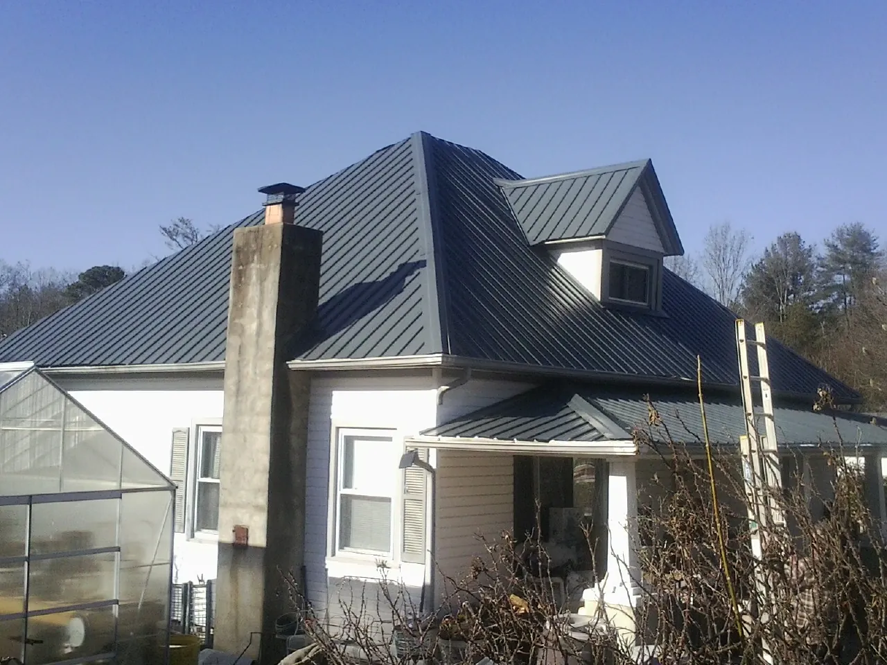 Dark blue standing seam metal roof on a white farmhouse with dormer — Slate & Tile Roof Repair by Roofing Brothers in West Chicago