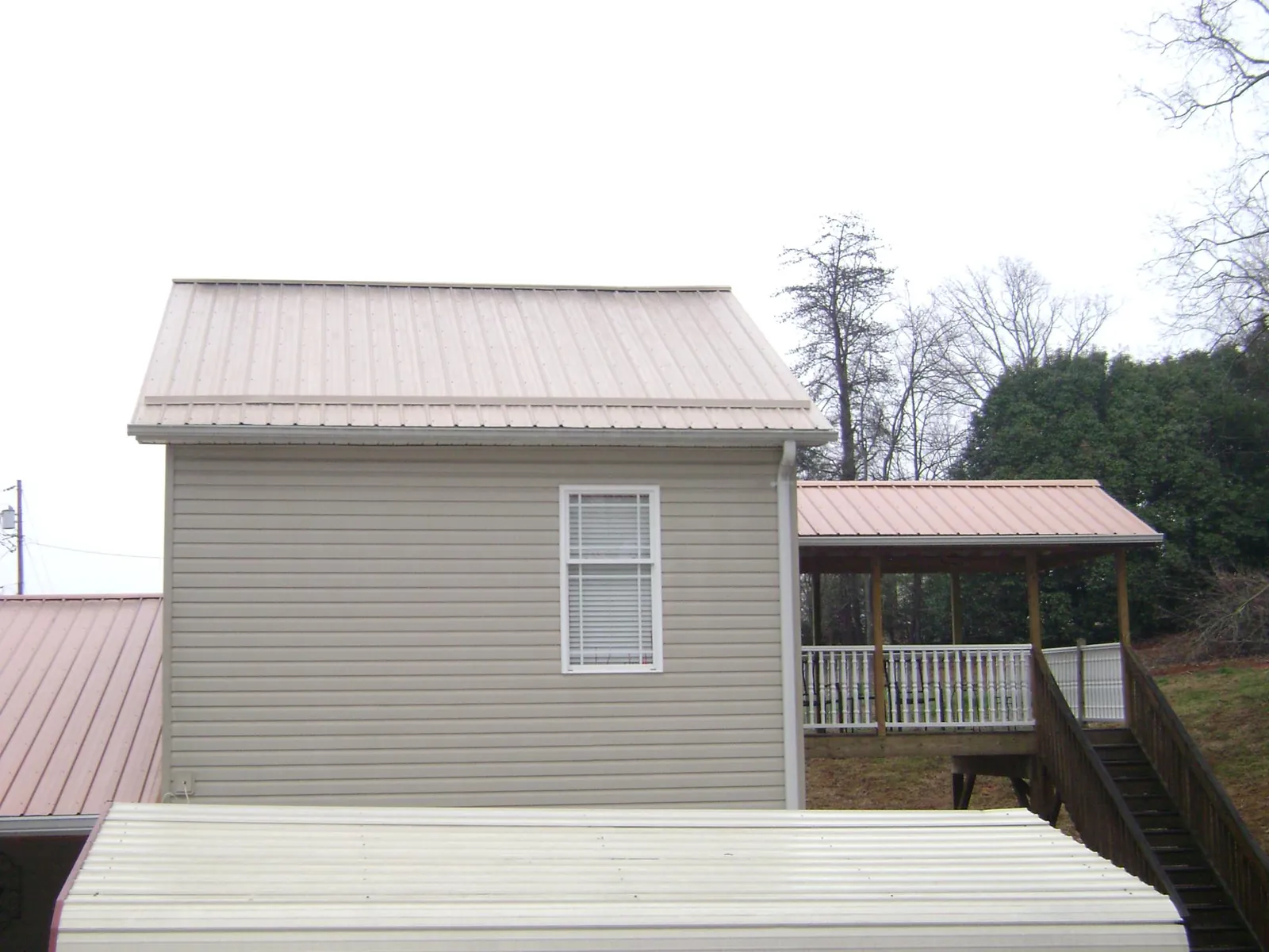 Tan metal roofs on a two story addition and attached porch, from a Roof Replacement job in West Chicago