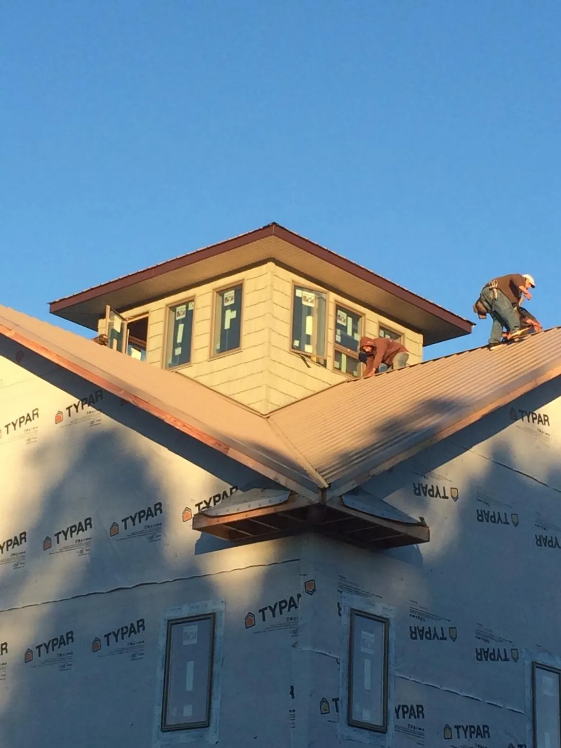Roofers working around a rooftop cupola on a new metal roof at sunset — Roof Waterproofing in West Chicago by Roofing Brothers